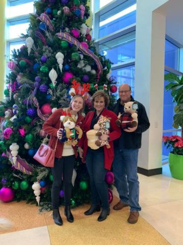 Western Sun members pose in front of christmas tree with donated toys for a donation drive