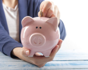 Female hands holding piggy bank and placing change inside