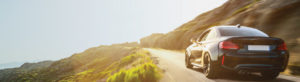 Sports car driving down picturesque mountainside view on a bright sunny day