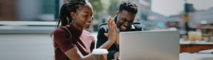 African American couple using laptop and high-fiving each other