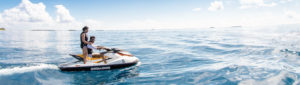 Young adult couple on jet ski on blue open water