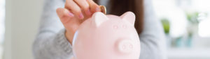 Young female adult hand placing change into piggy bank
