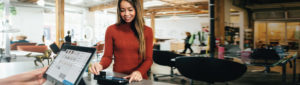 Asian American female in shopping boutique paying with debit card