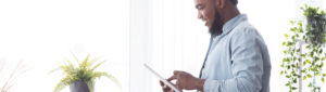 african american young adult smiling and using tablet to check e-statements